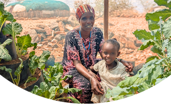 Mamma och barn sitter i ett grönsaksland i Kenya