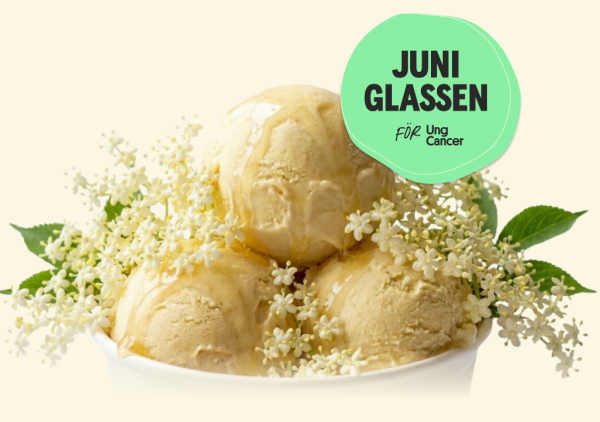 en ljusgul glass i vit bägare i flädersmak toppad med fläderblom och små gröna löv av fläder